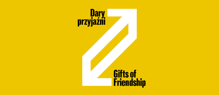 Grafika na żółtym tle przedstawia biały, geometryczny symbol dwóch połączonych strzałek skierowanych w przeciwne strony, tworzących dynamiczny skos. W lewym górnym rogu znajduje się czarny napis „Dary przyjaźni”, a w prawym dolnym jego angielski odpowiednik „Gifts of Friendship”.