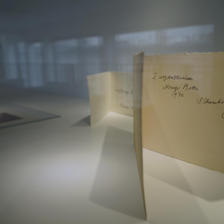 Fragment of the exhibition. In the foreground, an open postcard with a dedication.