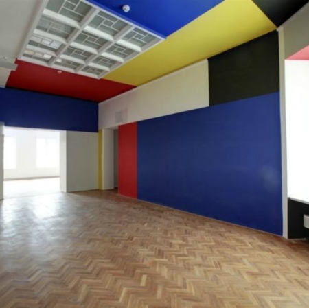 Sala Neoplastyczna, drewniana podłoga, ściany pomalowane w kolorach niebieskim, czerwonym, żółtym, białym i czarnym