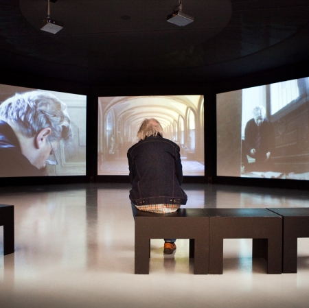 A man sitting on a chair, surrounded by screens