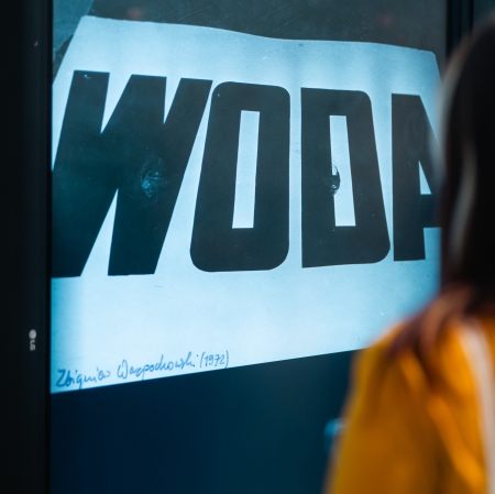 kobieta przedstawiona od tyłu, przed nią wyświetlony napis "woda".