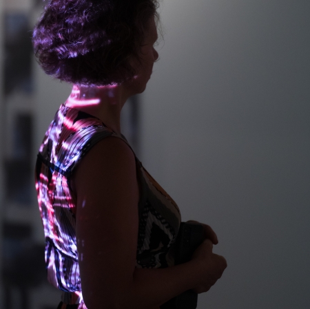 Na plecach stojącej profilem kobiety odbija się fragment iluminacji świetlnej. 
