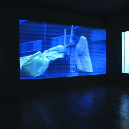 Sala wystawiennicza z wyświetlonymi filmami na ścianach