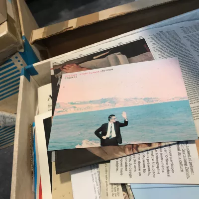 Photo of documents in cardboard boxes, on top there is a photo of a person against the background of the sea