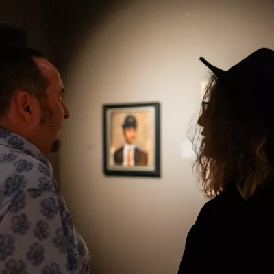 Dwie osoby stojące w przestrzeni wystawy, w tle obraz wiszący na ścianie