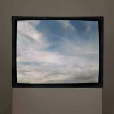 There is a TV where blue sky with white clouds is being broadcasted. 