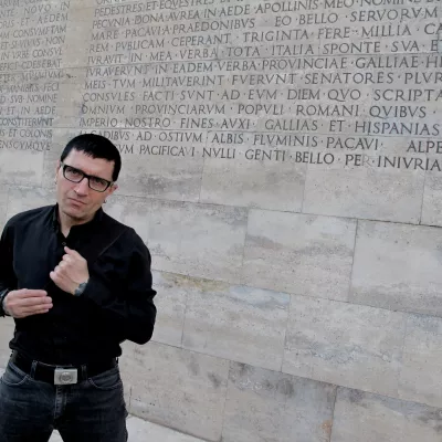 Kolorowe zdjecie męzczyzny na tle ścieny w beżowo szarym kolorze