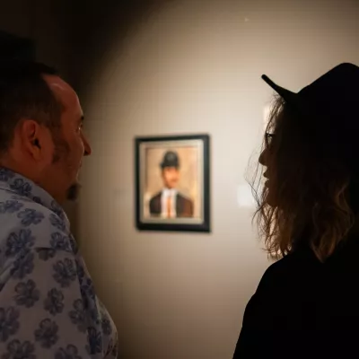 Dwie osoby stojące w przestrzeni wystawy, w tle obraz wiszący na ścianie