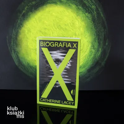Okładka książki „Biografia X” Catherine Lacey stojąca pionowo na czarnym tle. Na okładce dominuje jaskrawozielona litera X, pod którą widać zniekształcony czarno-biały portret twarzy. Za książką znajduje się intensywna, zielona poświata tworząca okrąg. W lewym dolnym rogu widoczne logo „klub książki ms”.